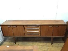 A mid century teak sideboard, with a pair of two door single shelf cupboards, flanking four drawers,