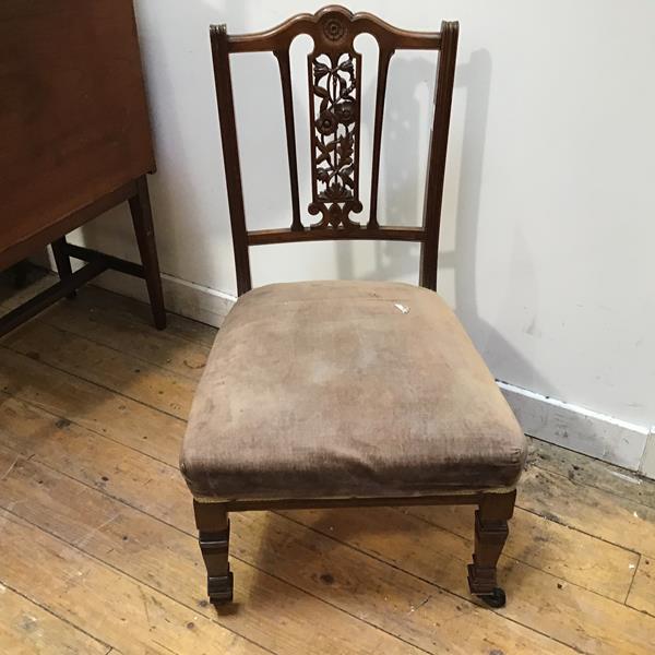 An Edwardian nursing chair pressed with central rosette above a pierced floral splat with