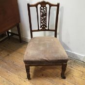 An Edwardian nursing chair pressed with central rosette above a pierced floral splat with