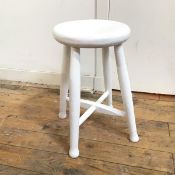 A white painted stool with circular seat on four turned supports united by stretchers (50cm x 30cm)