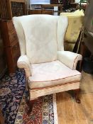 A modern Parker Knoll wing back armchair with foliate ivory upholstery and burnt orange piping, on