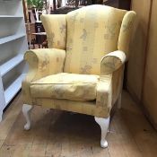 A wing back armchair in yellow foliate upholstery on painted front cabriole legs (102cm x 90cm x