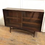 A mid century teak side cabinet, with two sliding glass doors and adjustable shelves, on turned