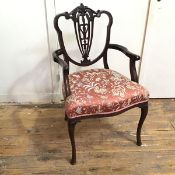 An early 20thc Georgian style open armchair, the shield back with elaborately carved top rail and