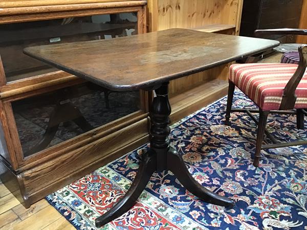 An early 19thc tilt top table, the oak top with rounded edges, on turned stem and tripod base (