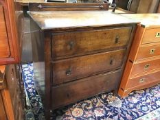 A 1920s oak chest of drawers with ledge back, the top with moulded edge above three long drawers, on