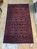 A Belouch rug in madder and blacks, the central panel with multiple flowerheads and medallions