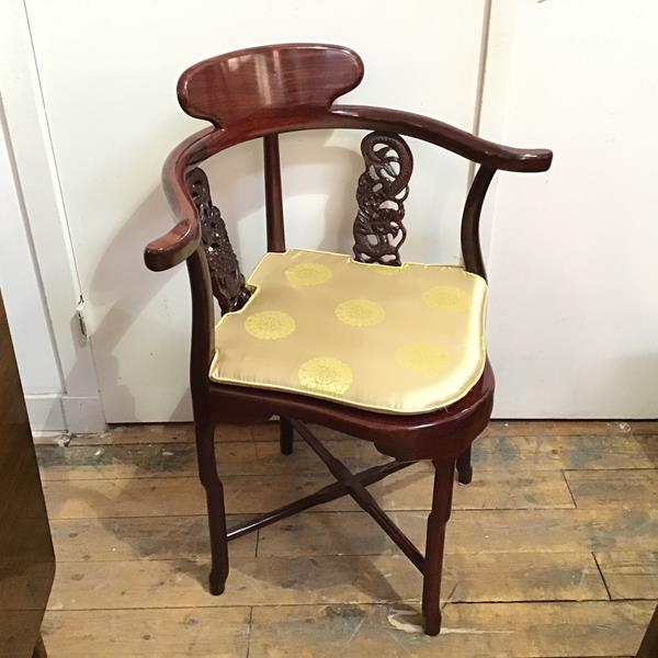 A modern Chinese hardwood corner chair, with dragon carved splats, above an upholstered pad seat