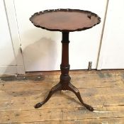A 19thc mahogany wine table with piecrust edge on turned stem with leaf carving to base, on tripod
