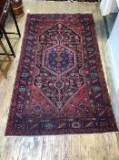A Kasak rug with central geometric medallion on madder field, within triple borders, all with