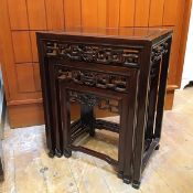 A set of three Chinese hardwood nesting tables, all with rectangular channelled tops, with carved