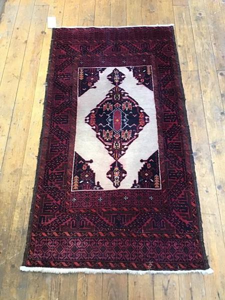 A North West Persian rug with central medallion on ivory field within a madder border with geometric