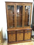 A modern mahogany bookcase, fitted three glazed doors and glass shelves, on base fitted three