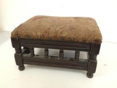 A 1920s upholstered footstool, with baluster frieze on turned feet (18cm x 32cm x 25cm)