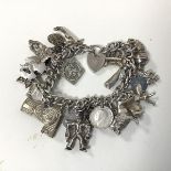 A 1930s/40s silver charm bracelet with charms including a lion, a thistle, boats, spinning wheel