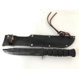 A US Vietnam War period jungle knife in leather scabbard, with wooden grip and marked US to blade (