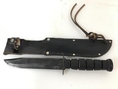 A US Vietnam War period jungle knife in leather scabbard, with wooden grip and marked US to blade (