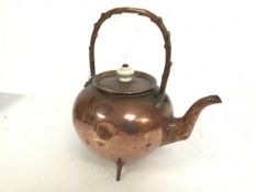 An Edwardian copper kettle of bulbous form with faux wood handle and spout on tripod feet (26cm x