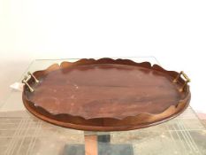 An oval wooden drinks tray with scalloped raised edge and brass handles to sides (57cm x 43cm)