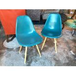 A pair of moulded plastic teal chairs on splay beech supports united by vertical X stretchers (