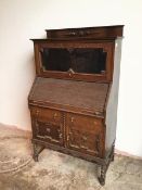 A 1920s/30s Tudor style oak bureau bookcase, the bookcase with glazed fold up door above a tambour