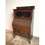 A 1920s/30s Tudor style oak bureau bookcase, the bookcase with glazed fold up door above a tambour