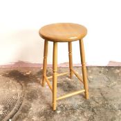 A beech stool with circular top on four turned supports united by box stretcher (60cm x 35cm)