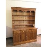 A modern pine dresser, the plate rack with upper shelf having acorn decorated apron, on turned