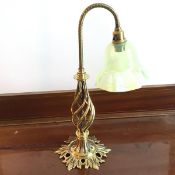 An Edwardian brass table lamp with ruffled vaseline glass shade, on spiral body with foliate base (