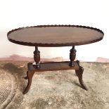 A mahogany Georgian inspired oval occasional table, with piecrust top, on two turned supports,