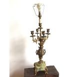 A candelabra with four foliate branches radiating from a single stem, emerging from classically