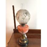 An Edwardian oil lamp with globular glass shade with applied flower and scrolling vine decoration,