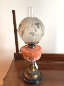 An Edwardian oil lamp with globular glass shade with applied flower and scrolling vine decoration,