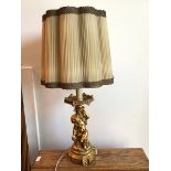 A modern gilt composition table lamp with faux drip tray and seated putti on column base, complete