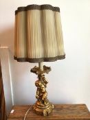 A modern gilt composition table lamp with faux drip tray and seated putti on column base, complete