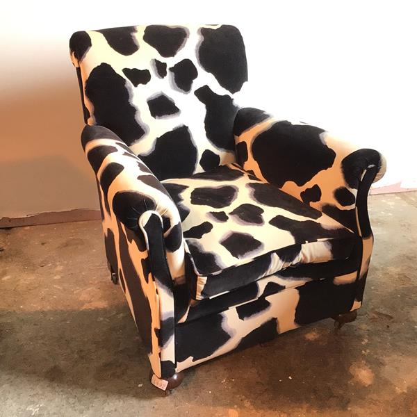 A club armchair reupholstered in animal print fabric, with curved headrest and arms on front bun