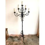 A large floor standing metal candelabra with five faux candles above drip trays, on C scroll and
