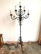 A large floor standing metal candelabra with five faux candles above drip trays, on C scroll and