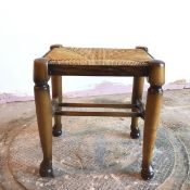 A footstool with woven rush seat, on turned supports united by stretchers (39cm x 36cm x 29cm)