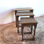 A set of three oak nesting tables on turned supports united by stretchers (largest: 48cm x 48cm x