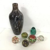A collection of glass paperweights, some with floral designs, and a Murano style cased glass vase (