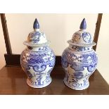 A pair of modern Chinese lidded blue and white vases, both decorated with dragons and mythical bird,