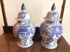 A pair of modern Chinese lidded blue and white vases, both decorated with dragons and mythical bird,