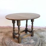 An oak oval swivel top drop leaf occasional table, on turned supports united by stretchers