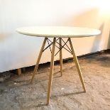 A white circular top dining table on four splay tapering beech supports united by vertical X