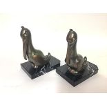 A pair of French Art Deco patinated metal bookends, Franjou, modelled as pelicans, each with glass