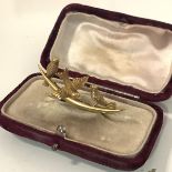 A late Victorian 15ct gold brooch, modelled as three birds perched on a tapering crescent bar,