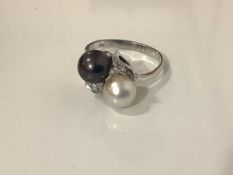 A cultured pearl and diamond dress ring, the two black and white pearls in a crossover setting