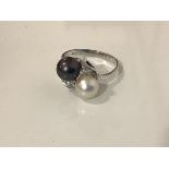 A cultured pearl and diamond dress ring, the two black and white pearls in a crossover setting