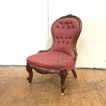 A Victorian walnut nursing chair, c. 1860, the shaped button-upholstered back with carved crest